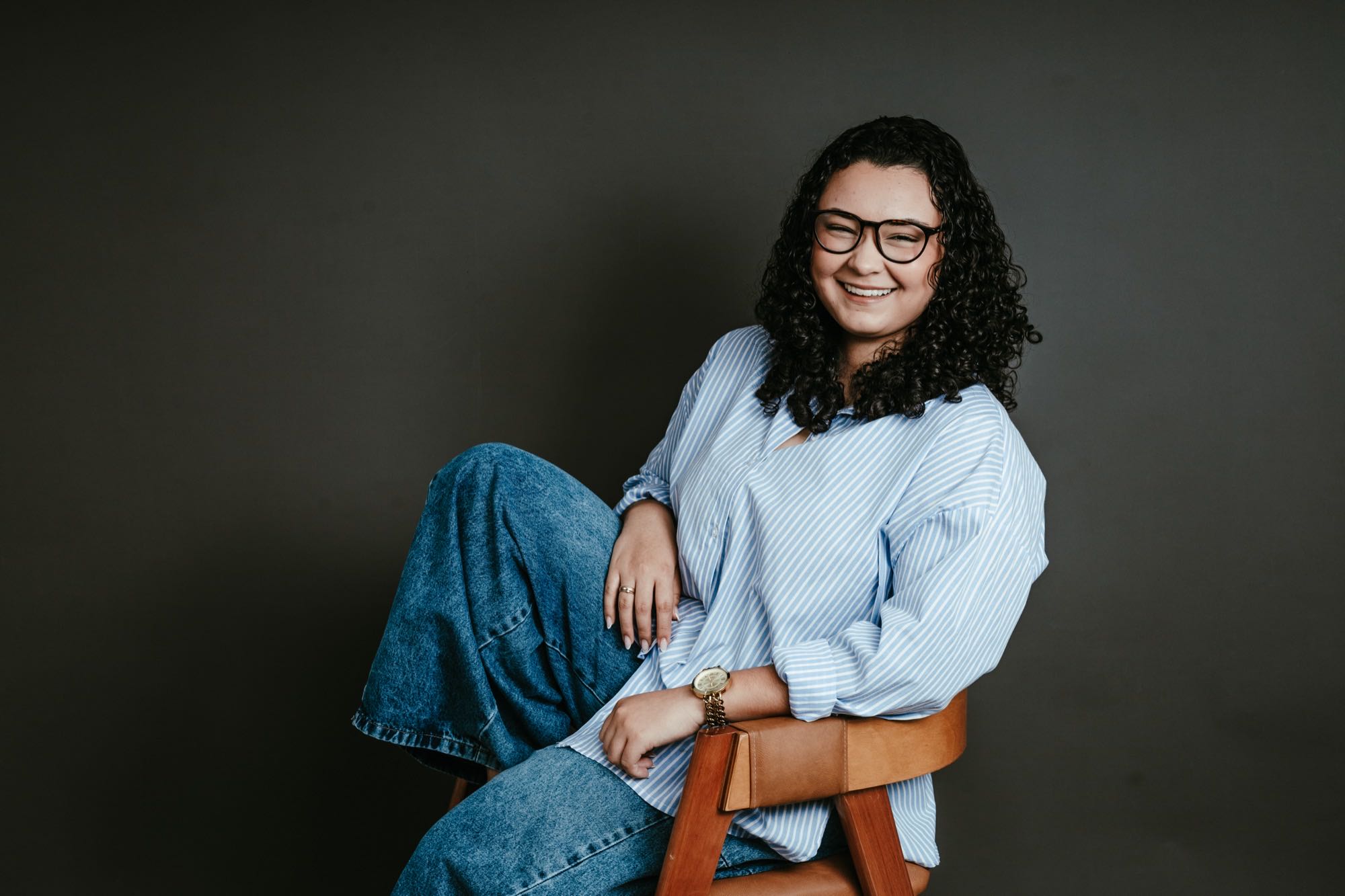 Joyce sentada numa poltrona, camisa azul